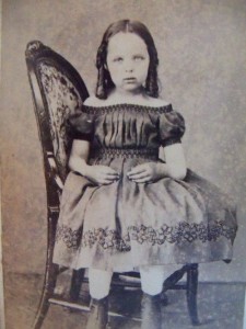 Deceased girl sat to the side on a chair so that a stand can support her body.